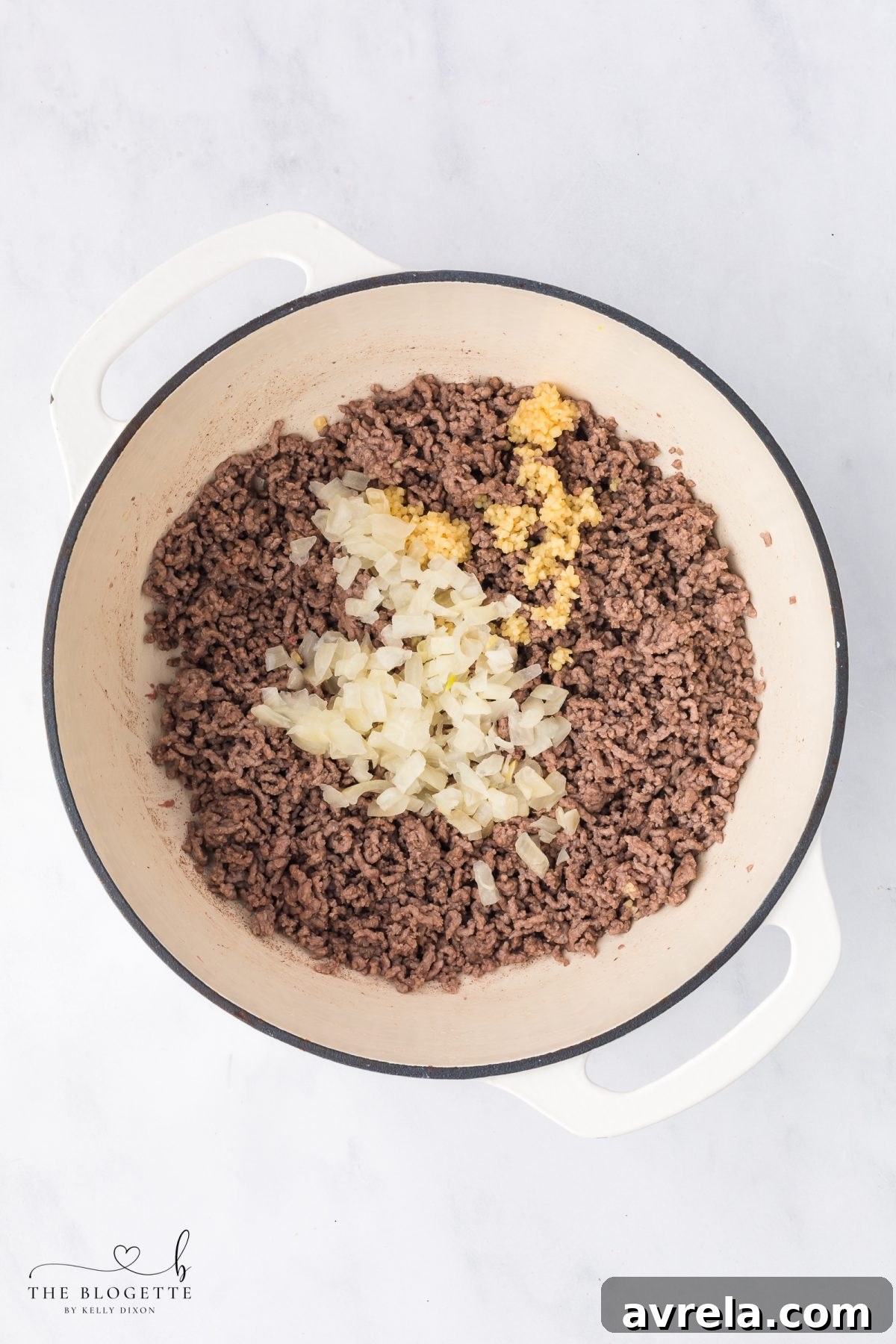 Sautéing minced garlic with the softened onions and ground beef.