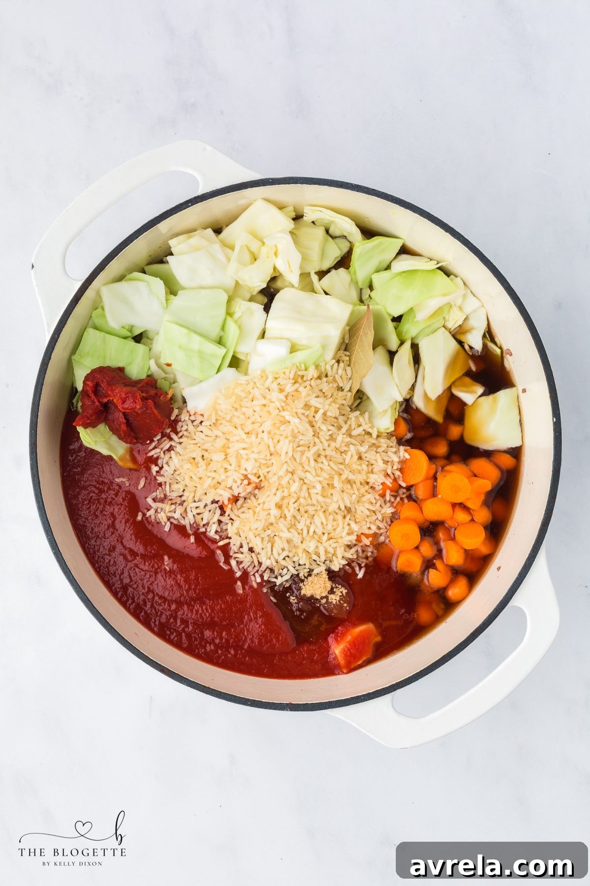 Adding all soup ingredients including cabbage, carrots, broth, and tomatoes to the pot with browned beef and aromatics.