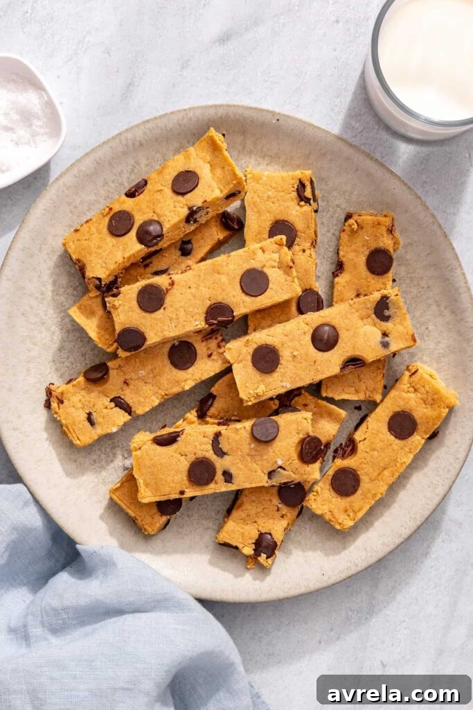 Chocolate chip peanut butter protein bars on serving plate next to glass of milk and cloth napkin