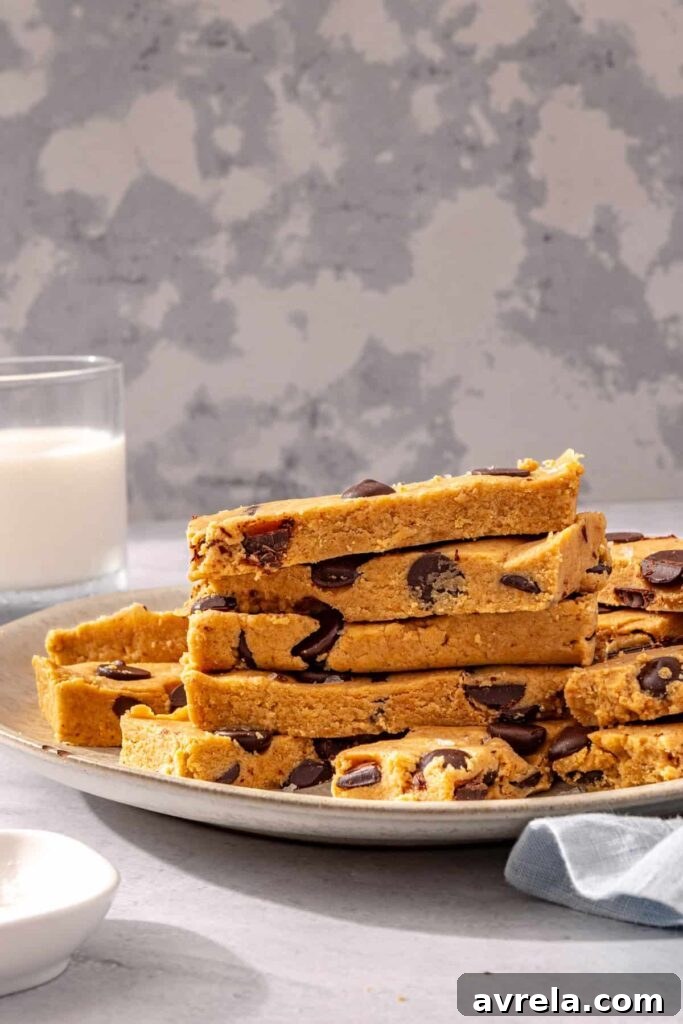 Stacked peanut butter protein bars on plate with glass of milk