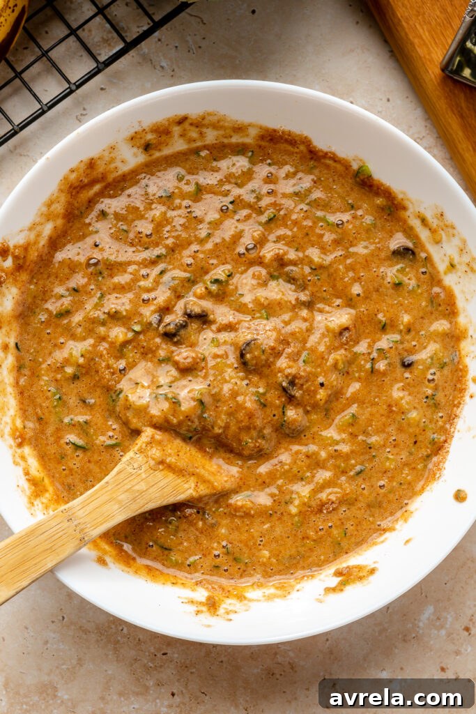 Grated zucchini being folded into gluten-free zucchini bread batter