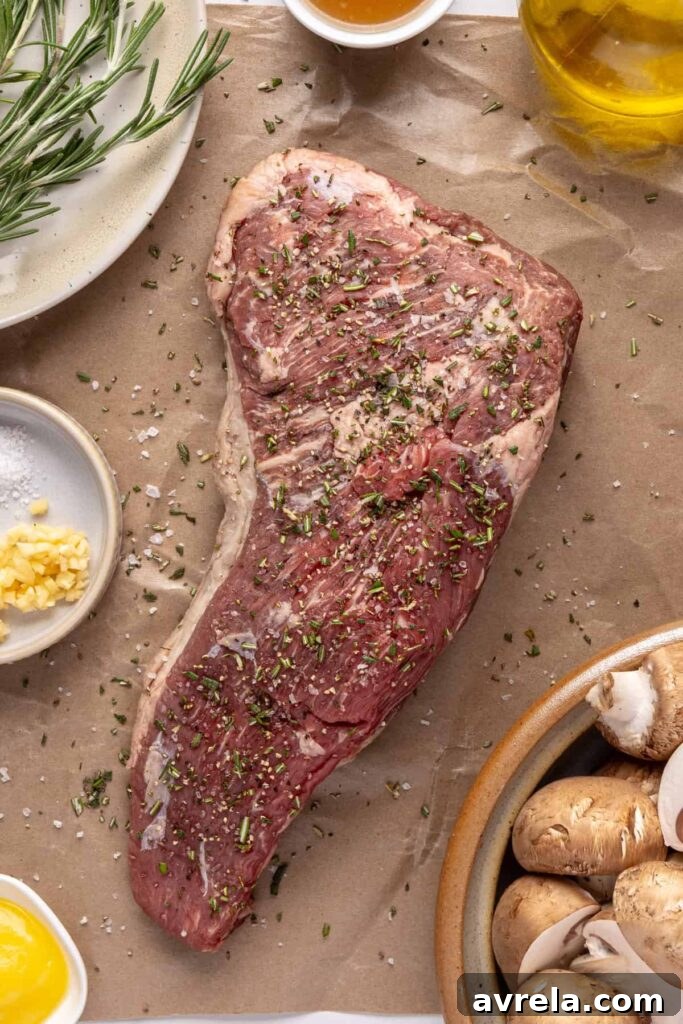 Juicy grass-fed tri-tip steak on a cutting board, seasoned with salt, pepper, and fresh rosemary