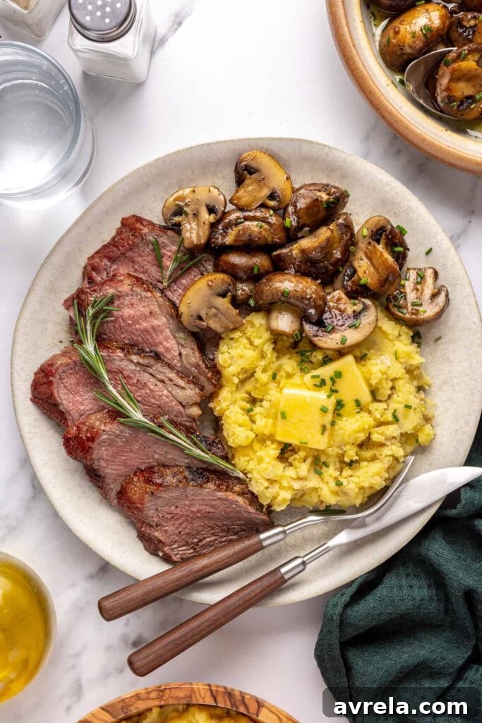 Tri-tip steak served with creamy mashed potatoes and garlicky mushrooms on a dinner plate