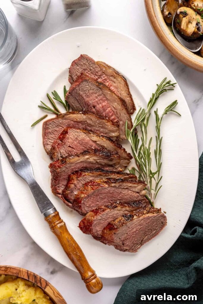 Sliced grilled tri-tip steak with rosemary and cracked black pepper, cooked medium-rare