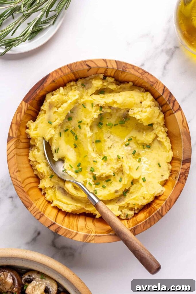 Creamy homemade mashed potatoes garnished with chopped chives, served in a wooden bowl