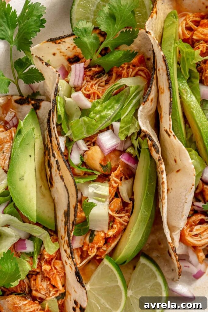 Healthy crockpot chicken tacos served with avocado, lime, and cilantro