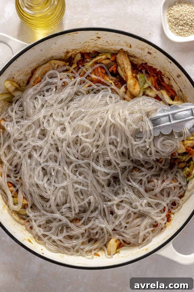 Sticky Honey-Garlic Chicken with Glass Noodles Recipe 15 Glass noodles being tossed with honey garlic chicken in a skillet
