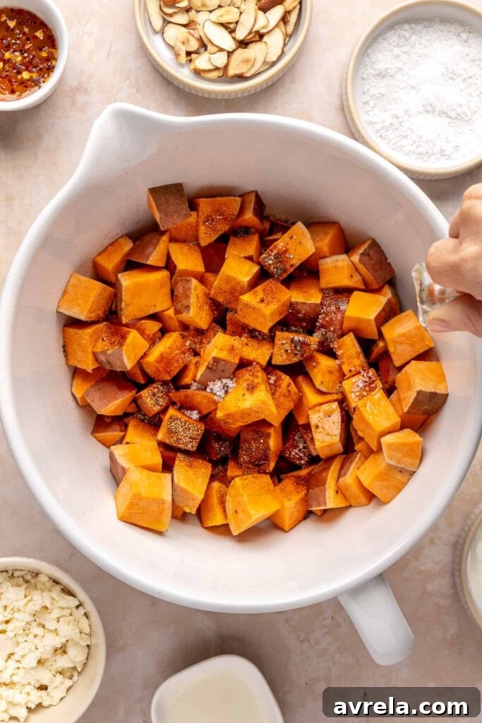 Maple-Roasted Sweet Potatoes with Whipped Feta and Hot Honey 4 drizzling olive oil over sweet potato cubes in a bowl before roasting