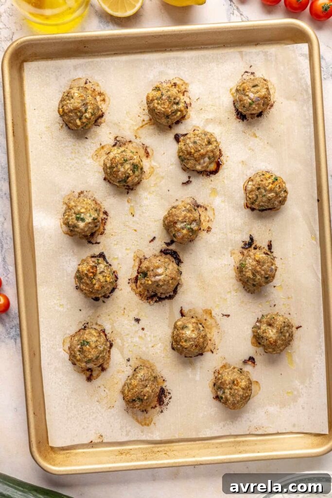 Tray of freshly baked Greek turkey meatballs seasoned with oregano and parsley.