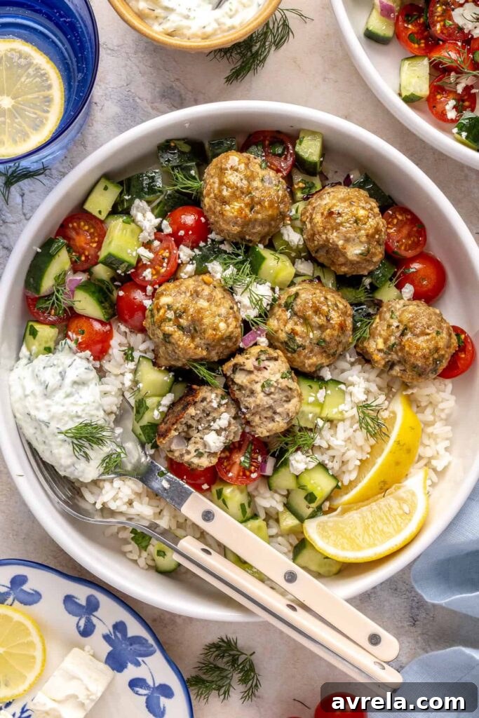 Greek turkey meatball bowl with rice, cucumber salad, and tzatziki.