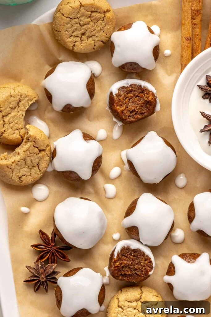 Finished gingerbread protein balls drizzled with coconut butter, styled on a baking sheet with cloves and ginger cookies, ready to enjoy