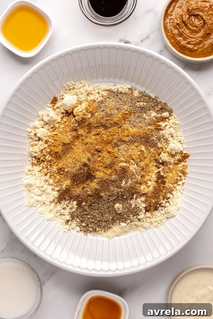 Dry ingredients for gingerbread protein balls: almond flour, protein powder, flaxseed, and warm spices in a mixing bowl