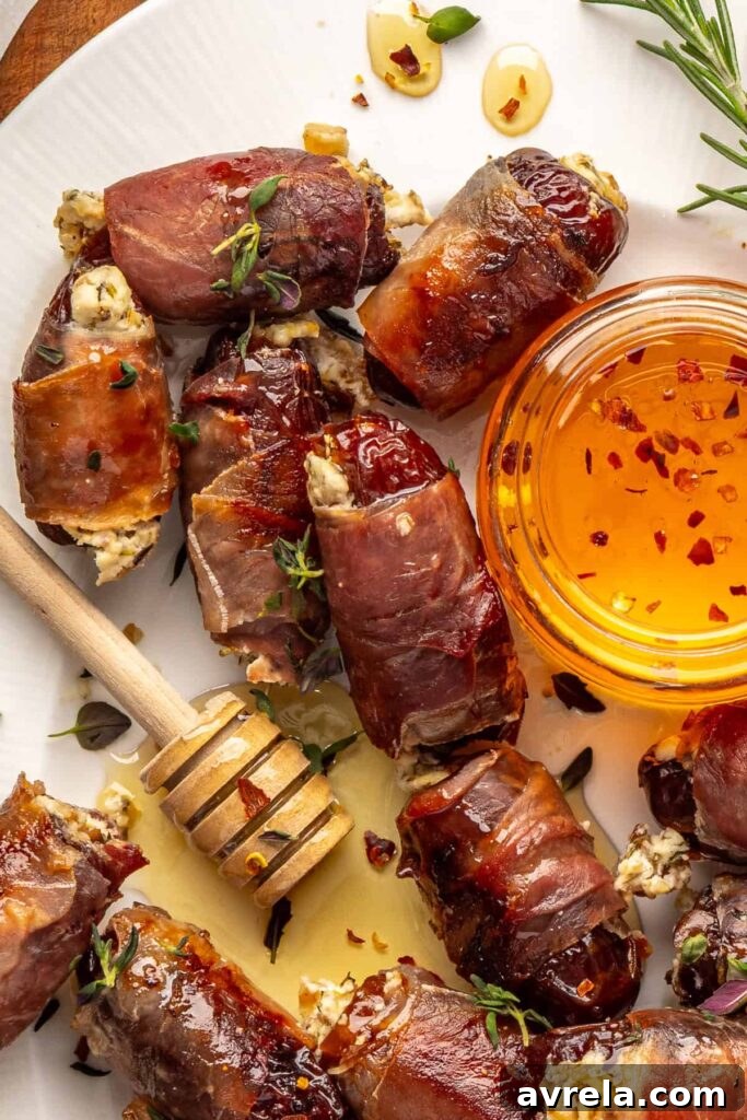 close-up of finished prosciutto wrapped stuffed dates on a serving tray, drizzled with hot honey and garnished with fresh thyme