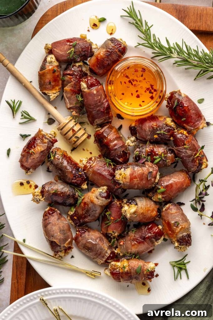 Finished prosciutto wrapped stuffed dates on a serving tray, drizzled with hot honey and garnished with fresh thyme