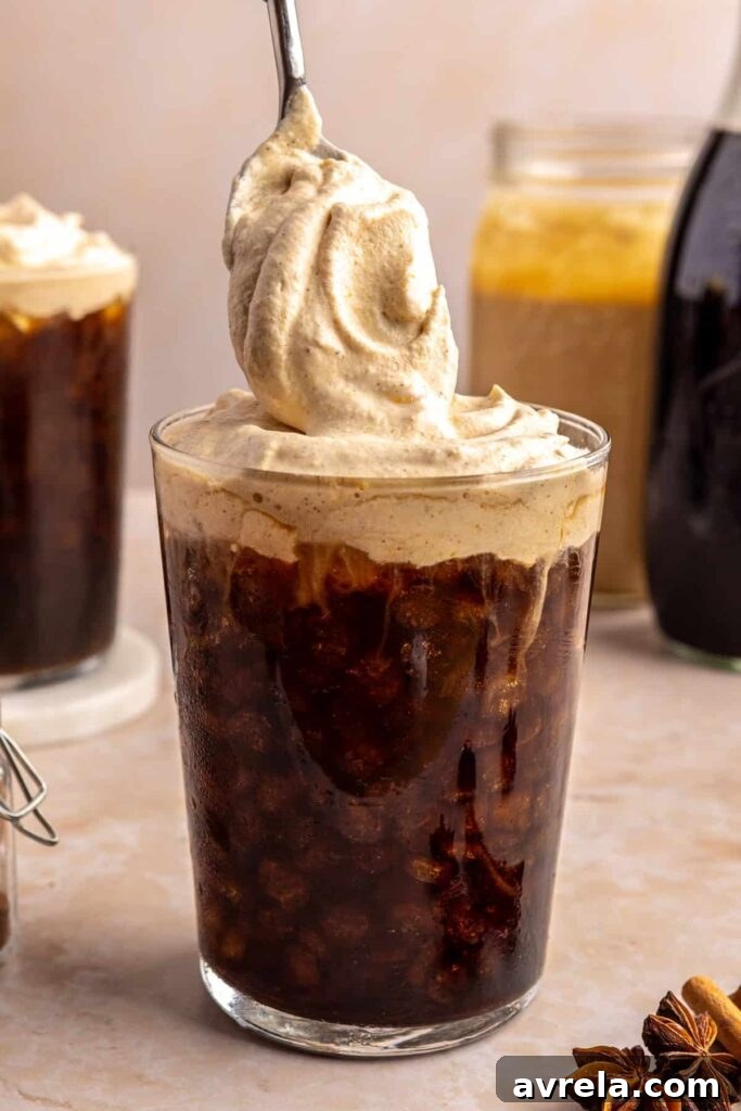 Pouring homemade pumpkin cold foam over iced coffee