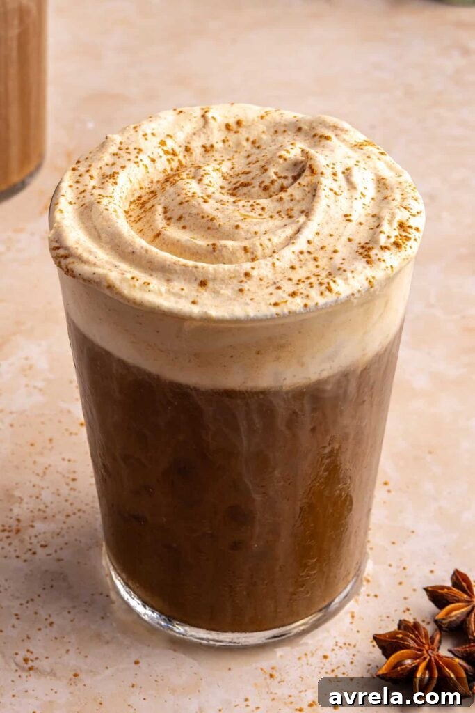 Pumpkin cold foam slightly mixed into iced coffee, still fluffy on top with a sprinkle of pumpkin pie spice