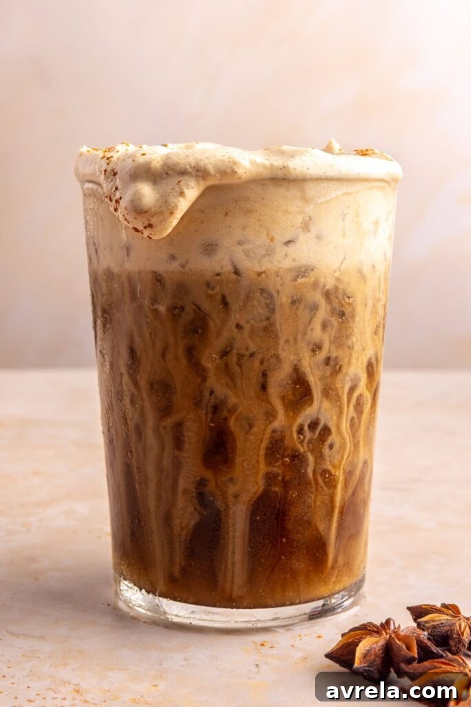 Layered pumpkin cold foam pouring over iced coffee edge