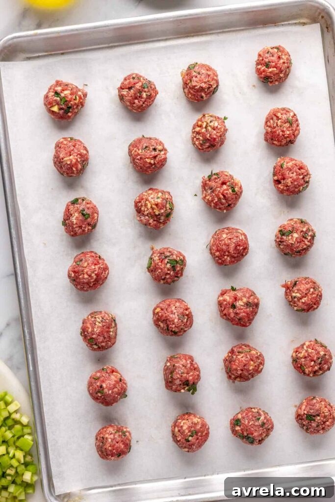 Beef meatballs on a parchment paper-lined sheet pan, ready to go into the Dutch oven for meatball soup
