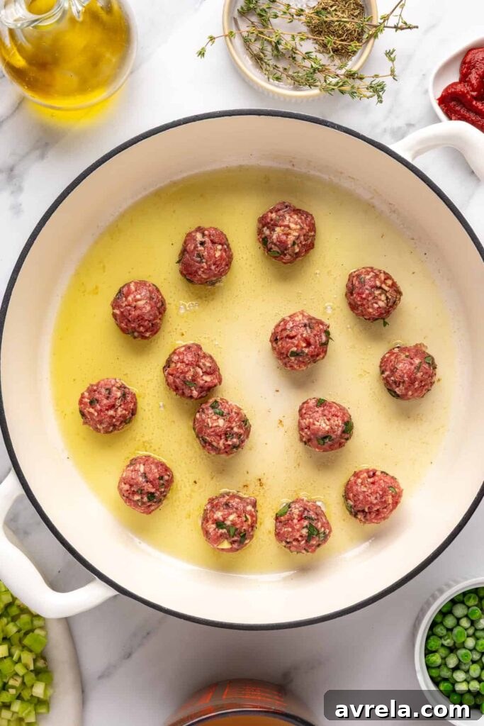 Browning beef meatballs in a Dutch oven for meatball soup