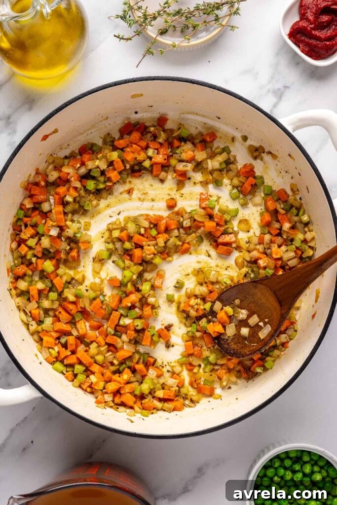 Sautéing onion, carrot, and celery with the cassava flour and garlic for beef meatball soup in a Dutch oven