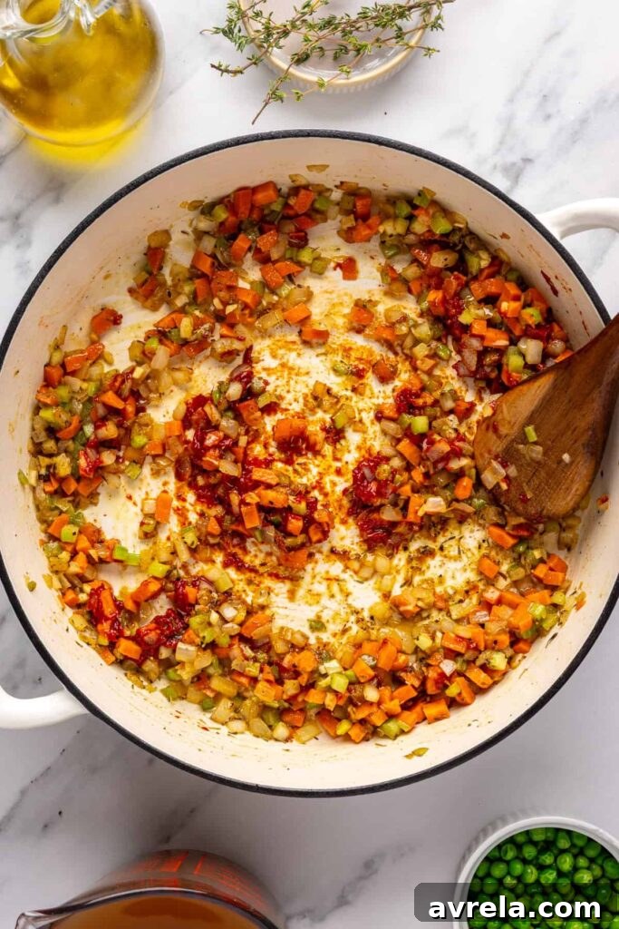 Stirring garlic, cassava flour, and tomato paste into sautéed vegetables for meatball soup