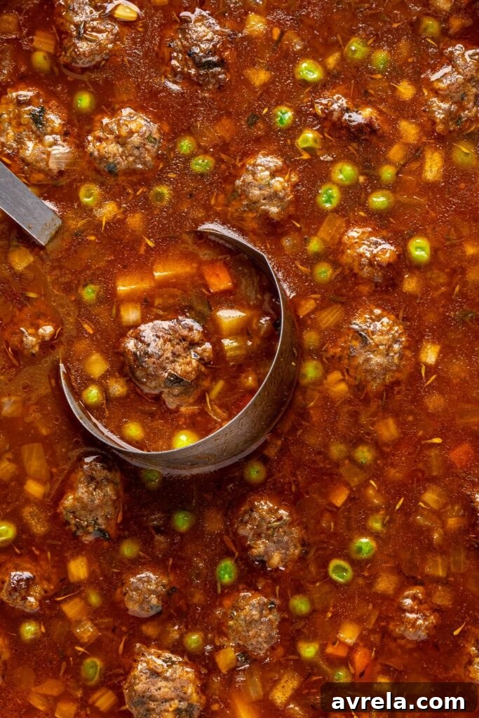 close-up shot of finished beef meatball soup in a Dutch oven with a soup ladle