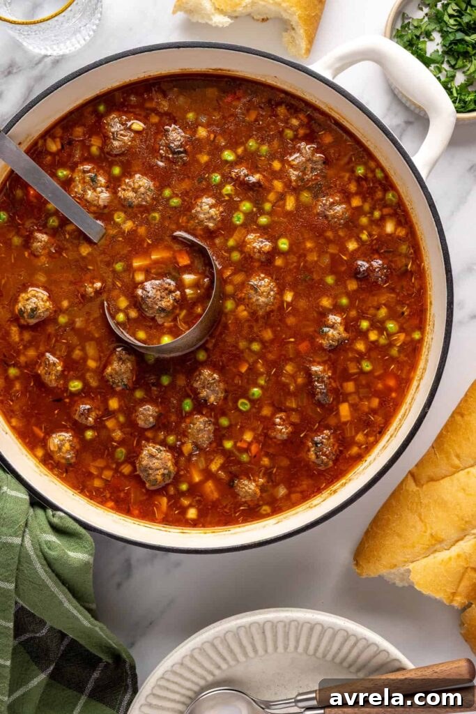 Overhead view of finished beef meatball soup in a Dutch oven with a soup ladle