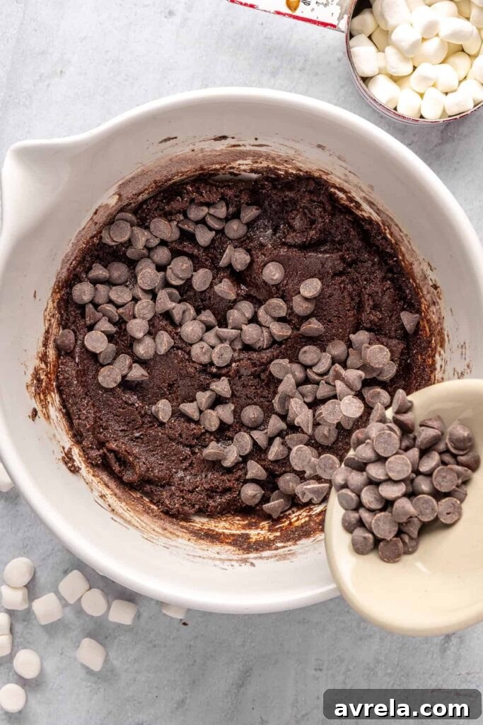 pouring chocolate chips into hot cocoa cookie dough