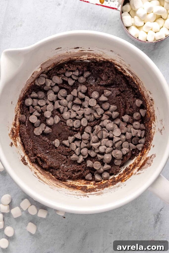 chocolate chips in a large mixing bowl on top of hot cocoa cookie dough, ready to be folded in