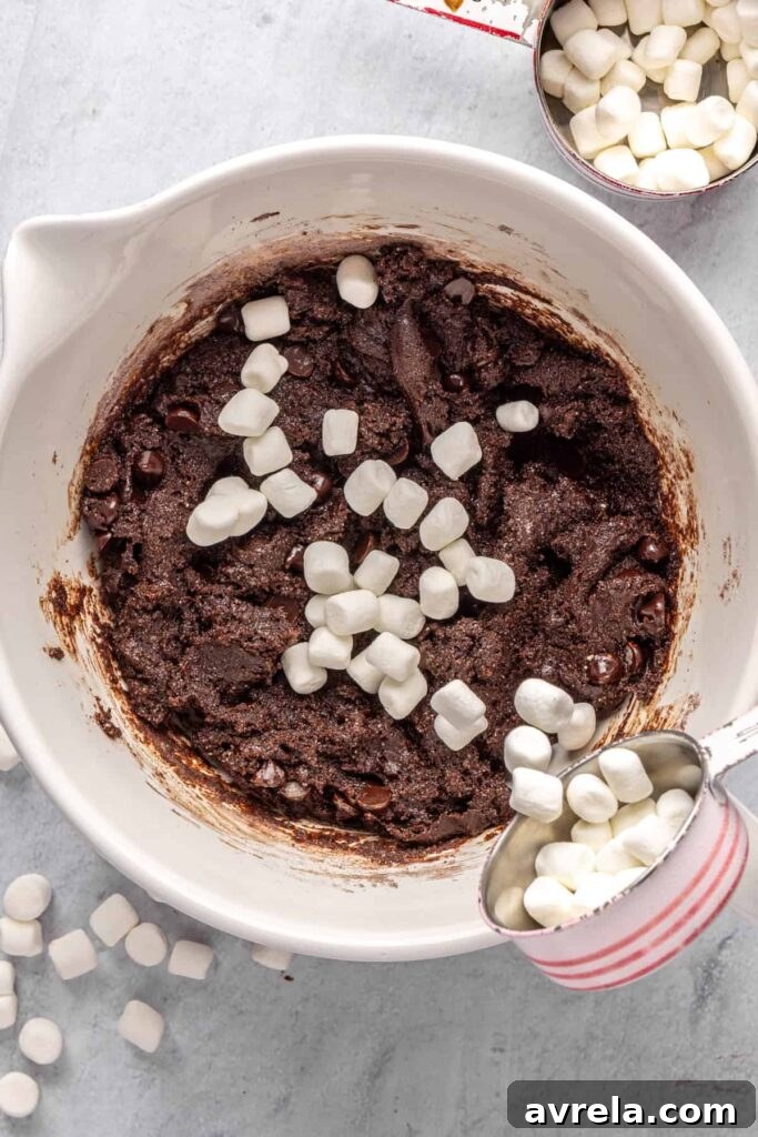 pouring mini marshmallows into hot cocoa cookie dough