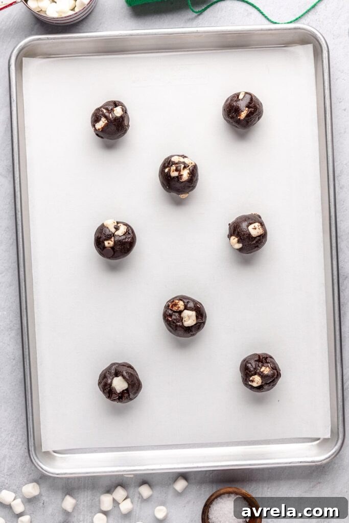 Preparing hot cocoa cookies for the oven with marshmallow topping