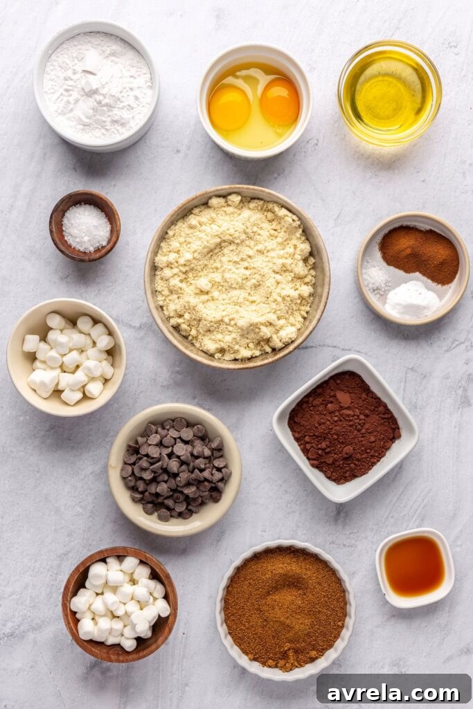 Overhead shot of ingredients for hot cocoa cookies, including almond flour, cocoa powder, chocolate chips, and mini marshmallows