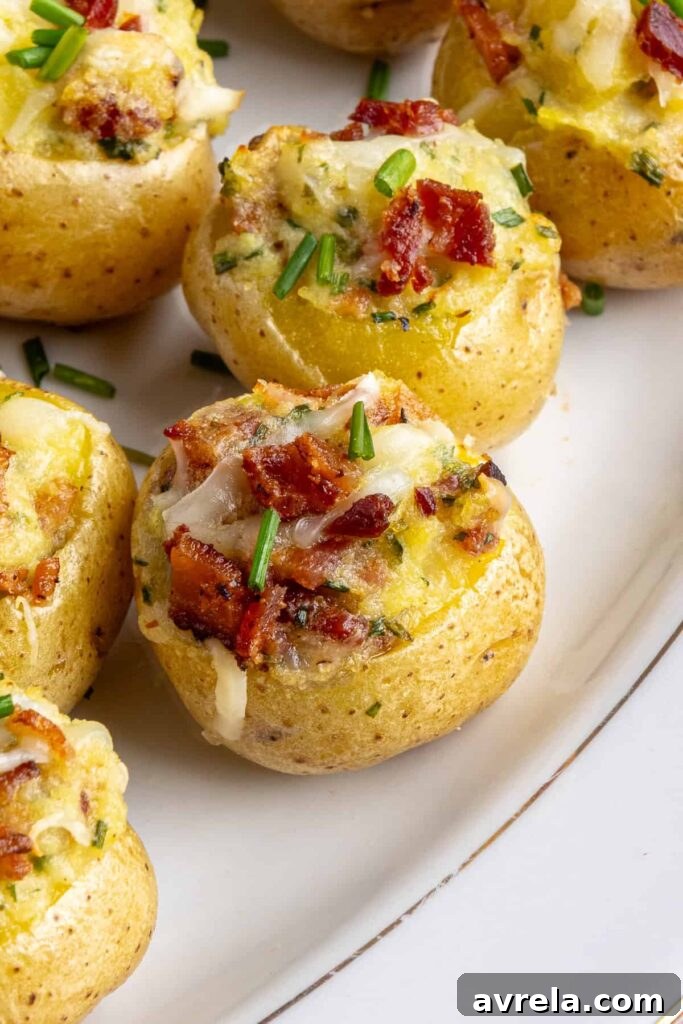 Angled view of creamy twice baked potatoes topped with bacon and chives on a serving plate