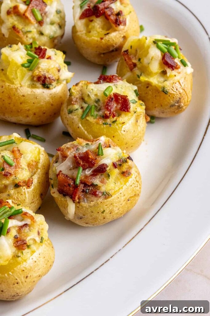 Angled view of creamy twice baked potatoes topped with bacon and chives on a serving plate