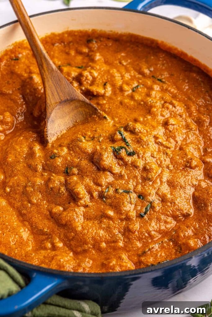 Close-up overhead shot of creamy homemade vodka sauce in a Dutch oven with a wooden spoon