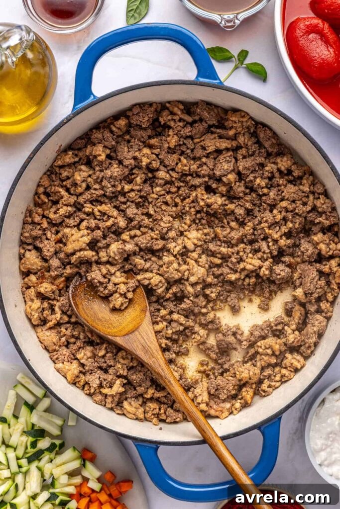 Ground meat cooking in a large pot for homemade vodka sauce, photographed from above
