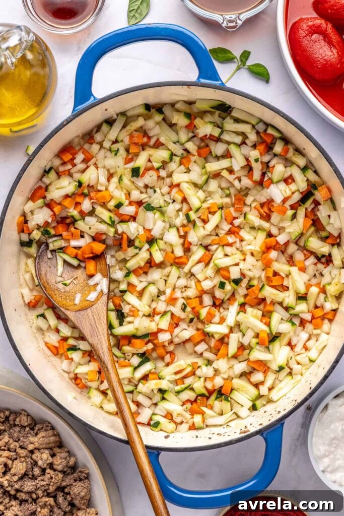 Overhead view of onion, zucchini, and carrot sautéing in a pot for hidden veggie vodka sauce