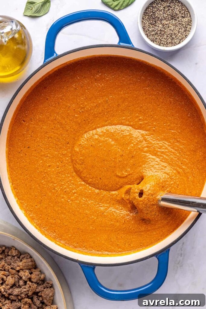 Immersion blender pureeing hidden veggie vodka sauce until smooth, overhead shot