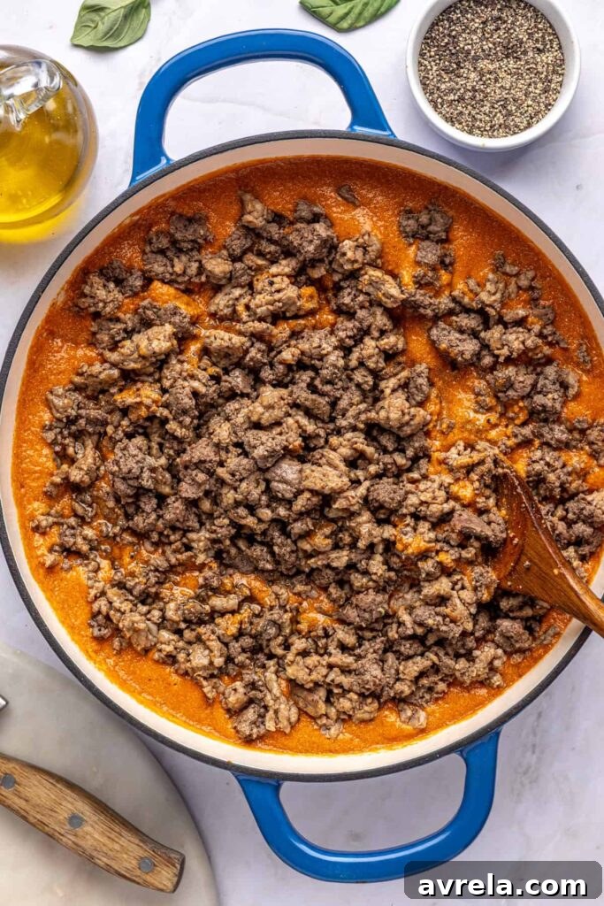 Overhead view of meat being added back into blended vodka sauce