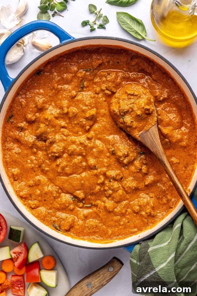 Overhead view of finished creamy homemade vodka sauce in a Dutch oven with a wooden spoon