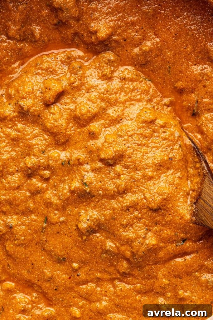 Smooth finished vodka sauce filling a Dutch oven, close-up overhead view with wooden spoon