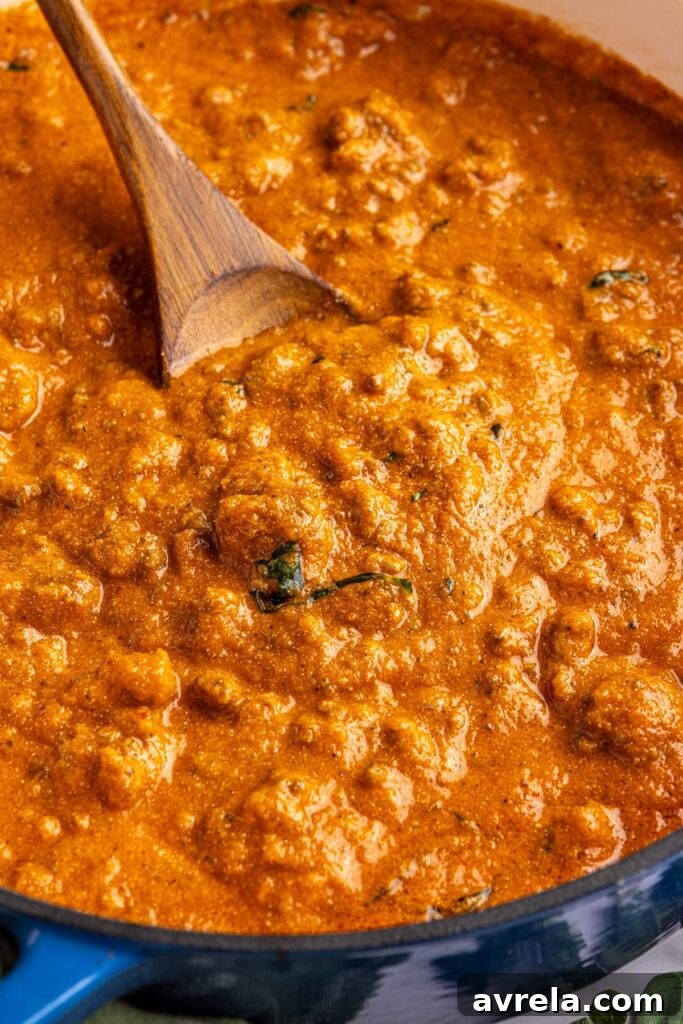Close-up overhead shot of creamy homemade vodka sauce in a Dutch oven with a wooden spoon