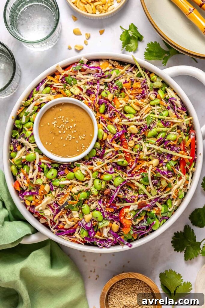 Overhead shot of crunchy peanut cabbage salad in white serving bowl with sesame peanut dressing and sesame seeds