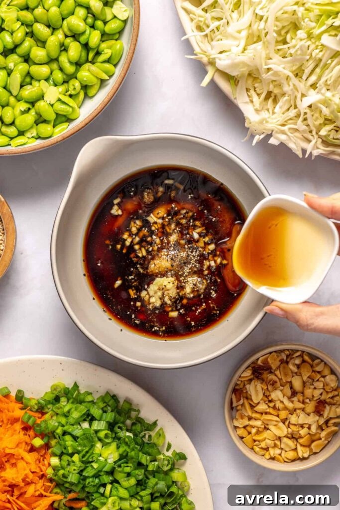 Adding peanut butter, sesame oil, rice vinegar, and lime juice to make peanut dressing for crunchy peanut cabbage salad