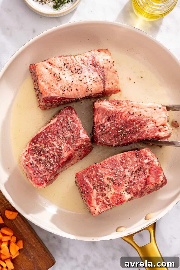 Short ribs searing in a pan until browned for slow cooker short rib ragu