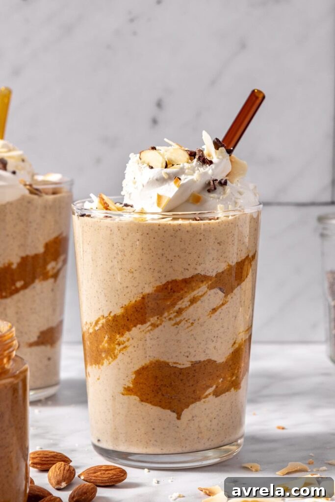 coconut milk smoothie with toppings and drizzled almond butter in a glass