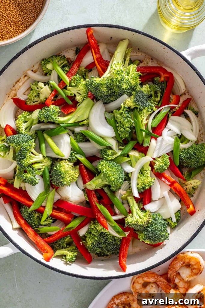 Vegetables sautéing in skillet for shrimp stir fry with broccoli, peppers, and onions