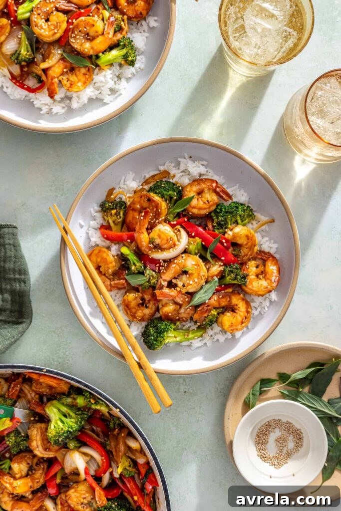Overhead shrimp stir fry bowl with rice, sesame seeds, and basil