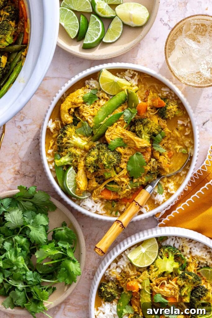 Slow Simmered Aromatic Chicken Curry 6 A bowl of creamy slow cooker chicken curry served over rice, with a stylish table setting including fresh cilantro and lime wedges.