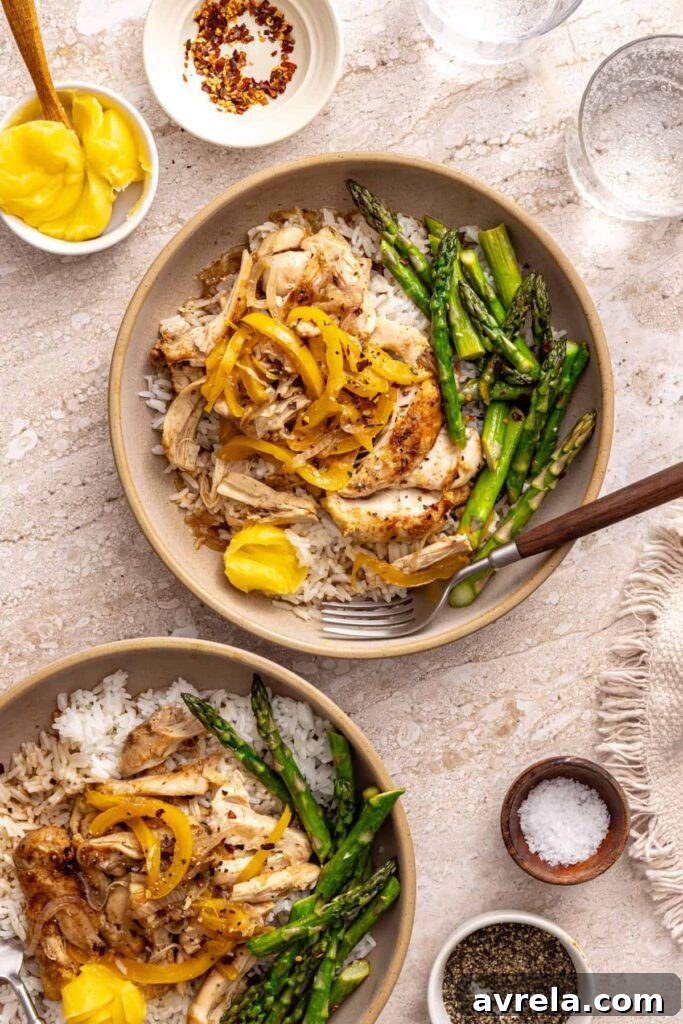 Wholesome Chicken Thigh Rice Bowls 2 Overhead view of two healthy chicken thigh rice bowls with asparagus and peppers on a rustic table setting